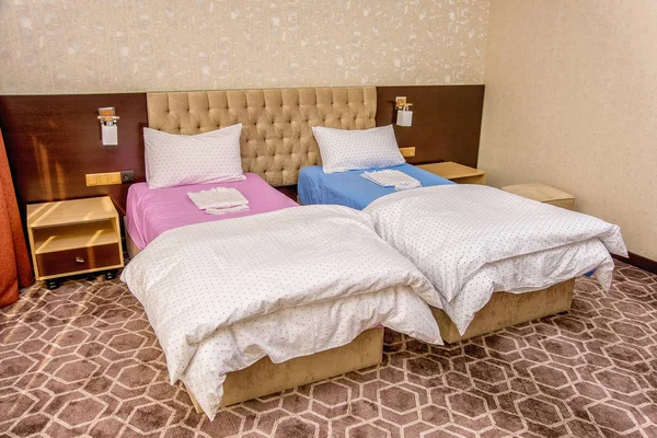 Bedroom interior with beautiful beds and linens. Single bed pink and blue. Double beds with white and color sheets. beige interior. soft poduishi blankets