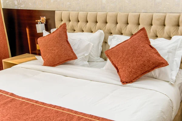 美丽的卧室内饰 双人床配有白色和橙色床单 美丽舒适的柔软枕头 家庭和酒店的床单 米色床 — 图库照片