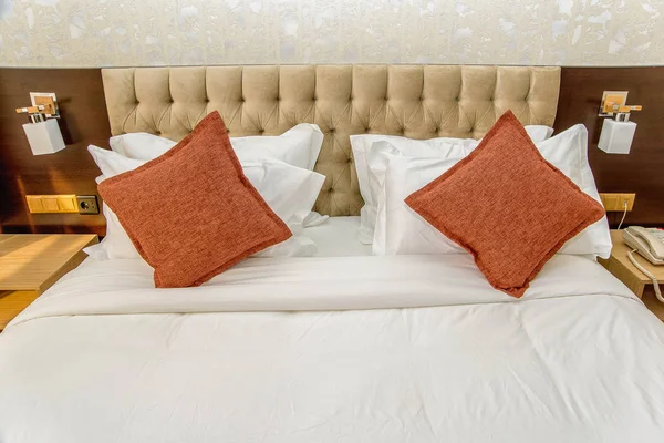 美丽的卧室内饰 双人床配有白色和橙色床单 美丽舒适的柔软枕头 家庭和酒店的床单 米色床 — 图库照片