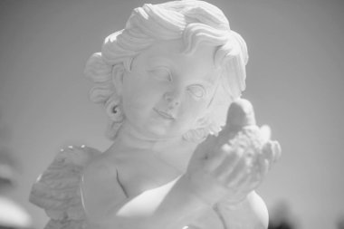 Melek heykeli. Bir melek gökyüzüne karşı portresi. Heykel kıvırcık saçlı küçük bir çocuk. Kültürel nesne parkta. Mermer mallar