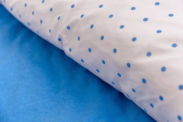 White cotton fabric in a blue circle. texture of sky-blue textile. pillow in white and blue pillowcase. soft cotton fabric for bed linen. White background with blue pattern.