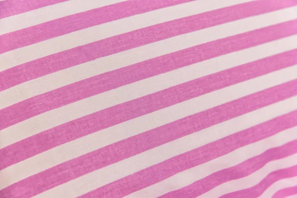 Cotton textile fabric with a pattern. Cotton with pink and white stripes. Pink textile background. Bed linen in white and pink cotton fabric colors. Production of textiles for the home. Fabric with a pattern.