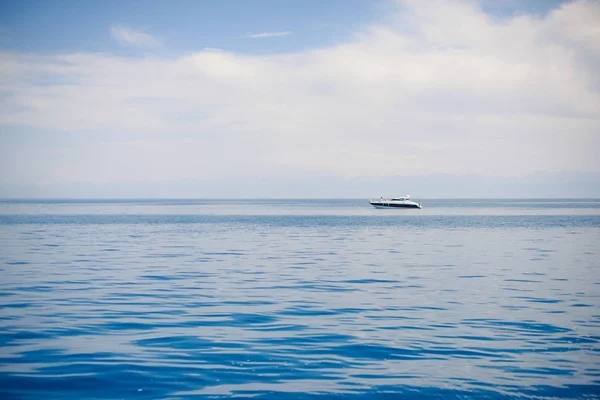 Boat in the blue sea. Yacht on the blue lake. Water transport. Boat with a gasoline engine. Transportation of people by sea. Water excursions on the lake Issyk Kul