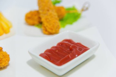 Çıtır nagitsy domates soslu beyaz bir tabak üzerinde. Ekmek kırıntıları içinde tavuk parçaları. Tavuk patates kızartması ve ketçap. Salata yaprakları ve et. Yemek yemek için.