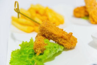 Çıtır nagitsy domates soslu beyaz bir tabak üzerinde. Ekmek kırıntıları içinde tavuk parçaları. Tavuk patates kızartması ve ketçap. Salata yaprakları ve et. Yemek yemek için.