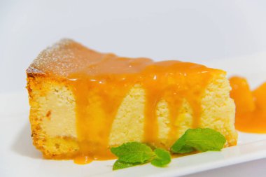 Akçaağaç şurubu ile peynirli kek. Pasta lezzetli ve taze nane yaprakları ile süslenmiş. Tatlı beyaz tabakta bal ile. Bütün aile için tatlı. Konuklar için lezzetli tedavi.