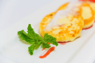 Tatlı şurubu ve krem şanti ile peynir kek. Süzme peynir gelen nefis tatlı. Serpilir cheesecakes pudra şekeri ve nane yaprakları ile dekore edilmiştir. Kırmızı tatlı şurubu.