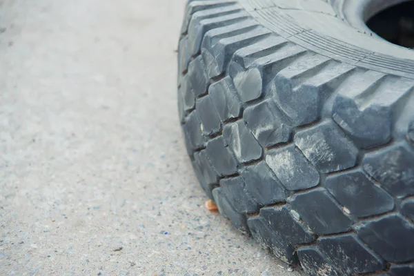 The tire lies on the ground. The tread of the old wheel lying on the pavement. Black rubber tire. The wheel of the car lies on the gray asphalt.