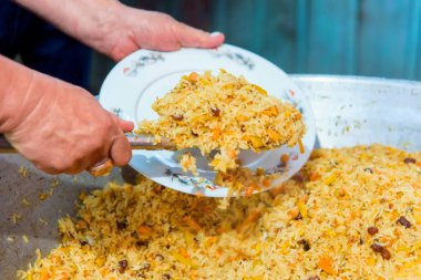 Yerel yemeğiniyiyormuşsun pilav. Bir adam yemek tabağına çalıyor. Güzel sunucu yemekleri. Pişirme pilav et ve kuru üzüm ile. Kıyılmış et sıcak bir yemek için. Taze ve lezzetli yemek.