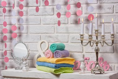 Çok renkli terry havlu. Sarı yeşil mavi ve mor pamuk havlular. Tekstil beyaz tuğla duvar arka plan üzerinde. Masanın üzerinde rulo ve katlanmış havlu.