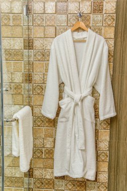 Beyaz bornoz için ev ve otel. Bornoz gözleme. Bornoz süet yavaşça krem rengi. Sıcak ve yumuşak kumaşlar. Yüksek kaliteli pamuk gömlekler. Banyoda bir askı erkekler için bornoz.