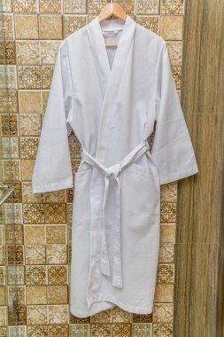 Beyaz bornoz için ev ve otel. Bornoz gözleme. Bornoz süet yavaşça krem rengi. Sıcak ve yumuşak kumaşlar. Yüksek kaliteli pamuk gömlekler. Banyoda bir askı erkekler için bornoz.