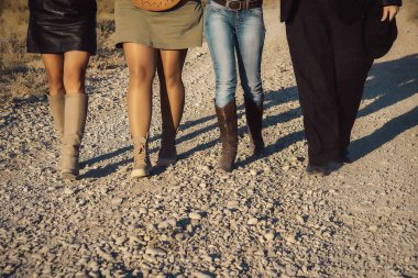 Erkek ve kadın bacakları farklı giysiler ve ayakkabı. Vintage kovboy çizmeleri. Taşların üzerinde yürüyen insanlar. Deri etek kız. Erkek pantolon ve ayakkabı. Mavi jeans ve tarçın bot.