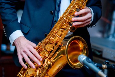 A man plays the saxophone. A man in a beautiful suit. Musical instrument saxophone. music for the soul and relaxation. Golden saxophone. Well-groomed hands of a musician. clipart