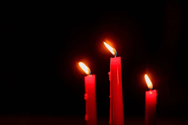 Red candles are burning. Candles for Valentine\'s Day. Background of the luminous scratches. Real fire candles on a black background. Candles in a beautiful suspension. Burnt candles. Flowed vox from candles.