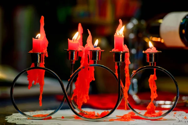 Red candles are burning. Candles for Valentine's Day. Background of the luminous scratches. Real fire candles on a black background. Candles in a beautiful suspension. Burnt candles. Flowed vox from candles.