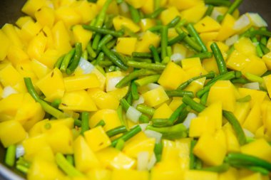 Patates kızartması yemek. Doğranmış patatesler kızarmış. Soğan ve yeşil sarımsak. Köpük bitkisel yağ kaynar. Bir vejetaryen yemek yapma. Lezzetli ve sağlıklı gıda.