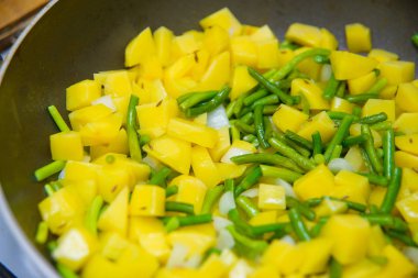 Patates kızartması yemek. Doğranmış patatesler kızarmış. Soğan ve yeşil sarımsak. Köpük bitkisel yağ kaynar. Bir vejetaryen yemek yapma. Lezzetli ve sağlıklı gıda.