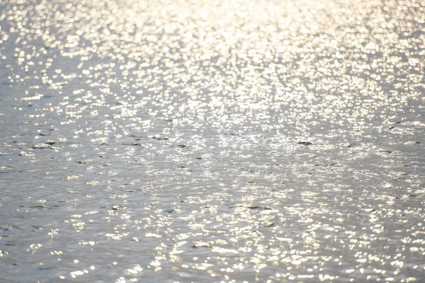 Water ripples. The glimmer of light on water. Silver gray and blue water with the reflection of the sun\'s rays. Photophone blue with white circles. Reflection of radiance on the water. Water surface and waves.