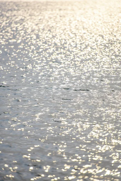 Water ripples. The glimmer of light on water. Silver gray and blue water with the reflection of the sun\'s rays. Photophone blue with white circles. Reflection of radiance on the water. Water surface and waves.