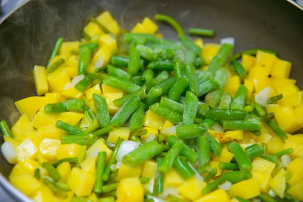 Cooking fried potatoes. Diced potatoes are deep-fried. Onions and green garlic. Boiling foaming vegetable oil. Making a vegetarian meal. Delicious and healthy food.