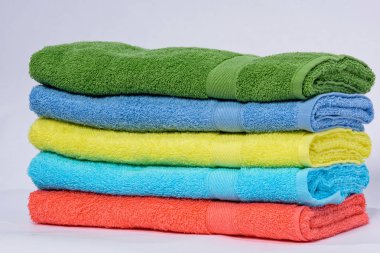 Ev dekorasyonu. Renkli havlu yığılmış. Kumaş dokusu. Beyaz bir arka plan üzerinde parlak havlu. Terry havlu. Kumaş türü.
