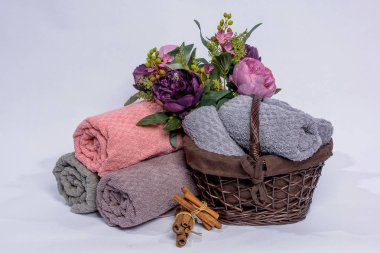 Bir sepet çiçekli havlu. Kumaş dokusu. Mor ve pembe çiçekler. Havlu rulo olarak yığılmış. Kumaş havlu kabartma desenli.