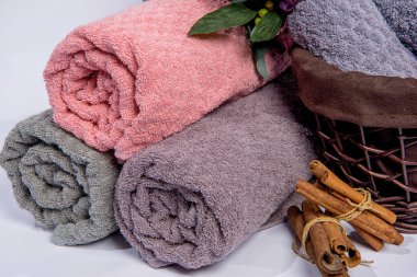 Bir sepet çiçekli havlu. Kumaş dokusu. Mor ve pembe çiçekler. Havlu rulo olarak yığılmış. Kumaş havlu kabartma desenli.