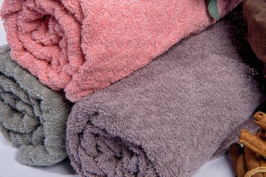 Bir sepet çiçekli havlu. Kumaş dokusu. Mor ve pembe çiçekler. Havlu rulo olarak yığılmış. Kumaş havlu kabartma desenli.