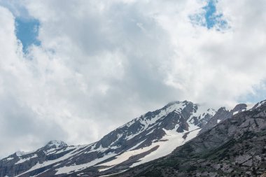 Karla kaplı dağlar. Mavi gökyüzü ile kalın bulutlar. Rocky Dağları doruklarına. Kazakistan dağ manzarası. Tepe Sairam-Su. Dağlarda hiking. Ugamsky dağ.