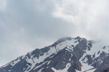 Karla kaplı dağlar. Mavi gökyüzü ile kalın bulutlar. Rocky Dağları doruklarına. Kazakistan dağ manzarası. Tepe Sairam-Su. Dağlarda hiking. Ugamsky dağ.