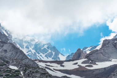 Karla kaplı dağlar. Mavi gökyüzü ile kalın bulutlar. Rocky Dağları doruklarına. Kazakistan dağ manzarası. Tepe Sairam-Su. Dağlarda hiking. Ugamsky dağ.
