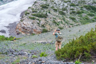 Adam dağlarda. Kar dağların kaplı. Bir adam bir cep telefonuna doğa fotoğraflar. Dağlarda hiking. Gezgin bir sırt çantası ile. Yalnız adam vahşi dağlarda. Dağ manzarası.