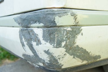 Gri köşe beyaz boya. Beyaz boya hasar görmüş. Plastik köşe üzerinde beyaz boya kask tarafından kalmış. Beyaz boya altında gri taban katmanı vardır. Beyaz araba tampon zarar.