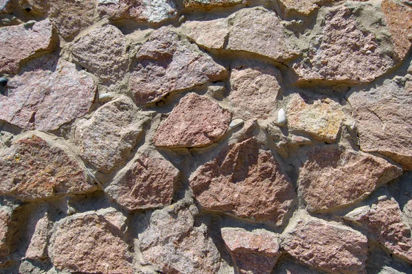 テクスチャの赤い石 赤御影石を壁紙します 壁には赤い小石が並んでいます 石はコンクリートが注がれています 装飾的な壁のトリム石 赤御影石のファサード 石のブロックの壁の構造 — ストック写真