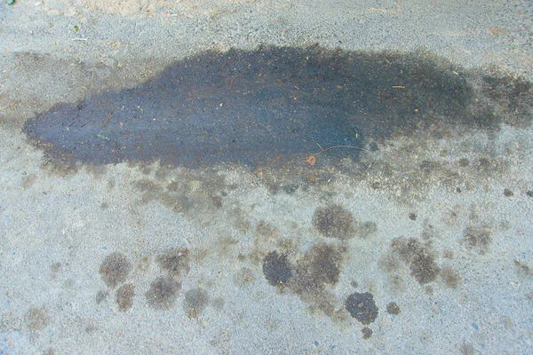 Oil stain on asphalt. Dirt on the side of the track. A big dirty spot on the road. Spilled oil on the highway. Dirty stain on the freeway.