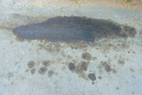 Oil stain on asphalt. Dirt on the side of the track. A big dirty spot on the road. Spilled oil on the highway. Dirty stain on the freeway.