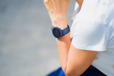 Adam eliyle saatin bileğinde bükülmüş. Şu andaki adamın elini üzerinde. Bir adam bir beyaz T-shirt onun dirsek eğildi. Siyah akıllı izle.