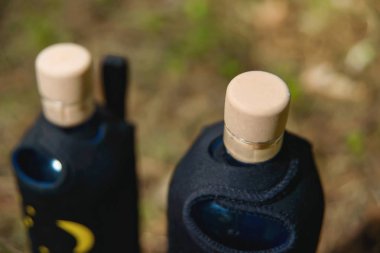 Cam şişe içme suyu bir kumaş çanta taşımak için. Çim arka plan üzerinde durmak şişe. Çizimleri hayvan malzeme kapağında. Mantar ile cam şişe.