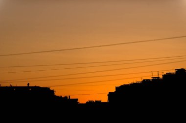 Turuncu günbatımı şehir. Yüksek katlı binaların çatıları. Elektrik kablo ve teller. Akşam kenti. Günbatımı.