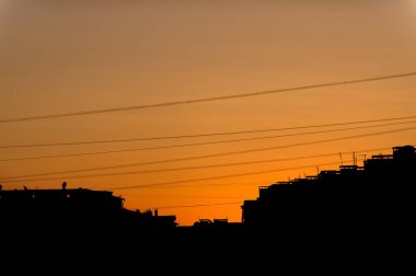 Turuncu günbatımı şehir. Yüksek katlı binaların çatıları. Elektrik kablo ve teller. Akşam kenti. Günbatımı.