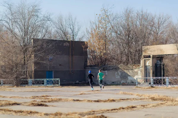 の周りを実行します ペアは トレーニングです ジョギングしている人 暖かい晴れた日に秋のトレーニング 古い放棄されたスタジアム 学生のパーソナル トレーニング — ストック写真