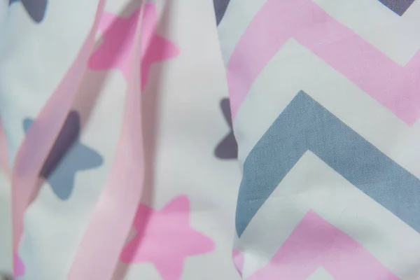 Pink ribbons on the corners of the pillow. Hanging satin ribbons. White pillows with gray and pink pattern. White, gray and pink shades. Cushion corners close-up.