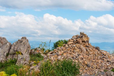 Yüksek dağlar. Taşlar ve cobblestones dağın üzerinde. Doğada bitki örtüsü. Dağlarda çiçeklenme. Taşlı yamaçlarda. Mavi gökyüzü. Doğa güneşli bir günde.