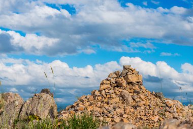 Yüksek dağlar. Taşlar ve cobblestones dağın üzerinde. Doğada bitki örtüsü. Dağlarda çiçeklenme. Taşlı yamaçlarda. Mavi gökyüzü. Doğa güneşli bir günde.