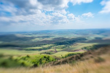 Mavi gökyüzü ile kabarık bulutlar. Beyaz cirrus bulutlar güneş tarafından aydınlatılmış. Yeşil Yayla küçük tepelerde. Dünya gökyüzü karşılamaktadır. Dünya havadan görünümü. Ufuk uzak. Bulutların altında güzel düz.