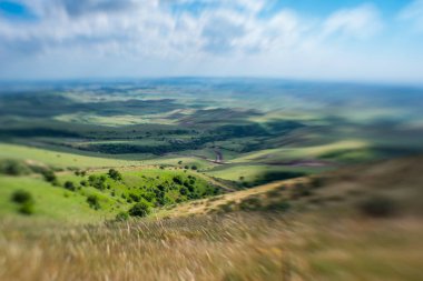 Mavi gökyüzü ile kabarık bulutlar. Beyaz cirrus bulutlar güneş tarafından aydınlatılmış. Yeşil Yayla küçük tepelerde. Dünya gökyüzü karşılamaktadır. Dünya havadan görünümü. Ufuk uzak. Bulutların altında güzel düz.