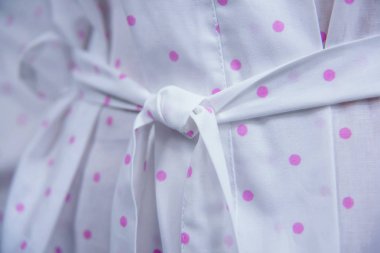 Pamuk bornoz. Tekstil. Beyaz elbise ile bir pembe polka dot yazdırma. Kumaş dokusu. Pamuk. Bornoz kemer insanlar. Otel ve otel için giyim. Kadın. Kol.