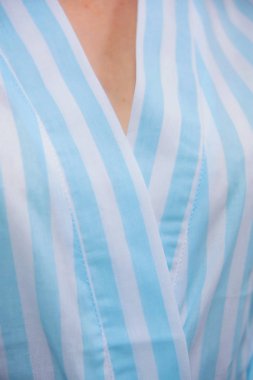 Pamuk bornoz. Tekstil. Bornoz açık mavi beyaz çizgili. Kumaş dokusu. Pamuk. Bornoz kemer insanlar. Otel ve otel için giyim. Kadın. Sarı saçlı. Kol.