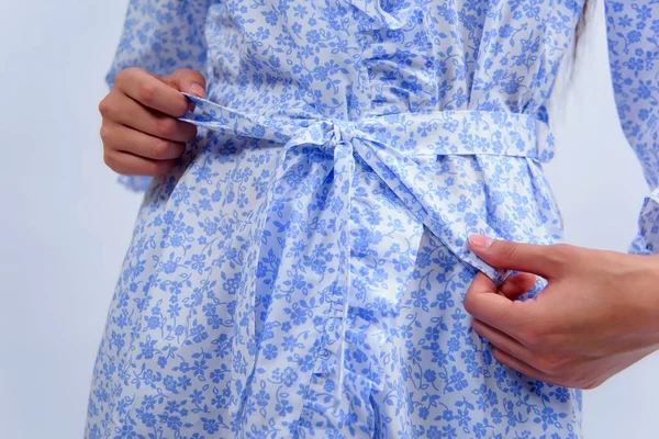 Cotton bathrobe. Textile. White robe with a blue floral print. The texture of the fabric. Cotton. Robe belt People. Clothes for hotels and hotels. Woman. Arm.